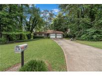 Charming single-story home with a two-car garage and a long driveway surrounded by lush greenery at 2935 Sawgrass Sw Trl, Lilburn, GA 30047