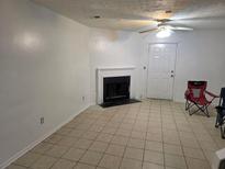 Living room with tile flooring, fireplace and ceiling fan with attached door at 437 Saint Ives Sq, Stone Mountain, GA 30083