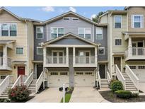 Charming townhome with two-story porch, attached garages, and well-maintained landscaping, creating inviting curb appeal at 1536 Liberty Nw Pkwy, Atlanta, GA 30318