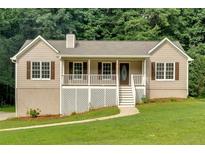 Charming home featuring a covered porch, white railings, and a well-maintained lawn at 225 Hitchcock Dr, Villa Rica, GA 30180
