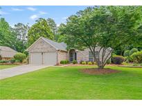 Charming brick home with a well-manicured lawn and a mature shade tree at 425 Greenmont Walk Ct, Alpharetta, GA 30009