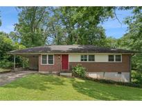 Charming brick home featuring a vibrant red door, attached carport, and mature landscaping at 4653 Ridgewood Dr, Forest Park, GA 30297