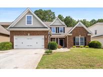 Charming brick home with well-manicured lawn and two-car garage at 320 Roland Manor Dr, Dacula, GA 30019