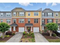 Attractive townhome with brick facade, colorful siding, driveway, one-car garage, and manicured landscaping at 771 Tulip Poplar Way, Lawrenceville, GA 30044