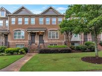 Brick townhome featuring a landscaped front yard and a welcoming entrance with brick steps at 7850 Willoughby Ct, Alpharetta, GA 30005