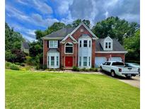 Charming two-story brick home with a well-manicured lawn and attached two-car garage at 703 Overlook Point, Woodstock, GA 30189