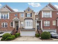 Attractive brick townhome with a two-car garage, manicured bushes, and a well-kept lawn at 1286 Creekside Se Ter, Smyrna, GA 30082