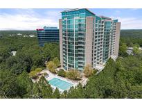 A high-rise condominium building overlooks a pristine pool surrounded by lush trees and neighboring buildings at 3300 Windy Ridge Se Pkwy # 809, Atlanta, GA 30339