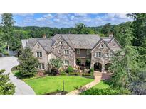 Stunning stone-and-brick home featuring a manicured lawn and a stone walkway leading to an arched front entrance at 4745 Cuyahoga Cv, Suwanee, GA 30024