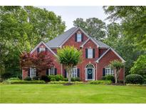 Charming two-story brick home with a lush green lawn and mature landscaping at 610 Woodstream Ct, Roswell, GA 30075