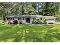 Charming one-story home with a manicured lawn, grey siding, and mature landscaping at 1467 Hewatt Rd, Lilburn, GA 30047