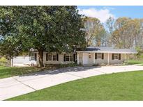 Charming single-story home with a well-manicured lawn, mature tree, and paved driveway at 3556 Riley Rd, Douglasville, GA 30134