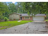 Split-level home with brick and siding, attached garage, and mature trees surrounding the property at 6503 Tent Valley Dr, Riverdale, GA 30296