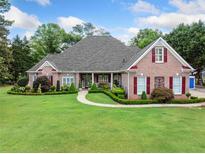 Beautiful brick home featuring manicured lawn, lush landscaping, and red shutters at 84 Nw Gloster Nw Rd, Lawrenceville, GA 30044