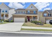 Charming two-story brick home featuring a well-manicured lawn, two car garage, and inviting front porch at 4349 Northmark Ln, Buford, GA 30518