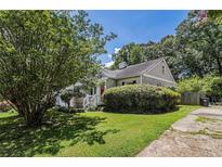 Charming home with a well-maintained lawn and lush greenery, and a bright red front door at 1932 Neely Ave, Atlanta, GA 30344