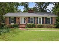 Charming brick home with manicured lawn, black shutters, and brick steps to the front door at 59 Oakmont Nw Dr, Marietta, GA 30064