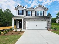 Charming two-story home featuring brick accents, a two-car garage, and a welcoming covered porch at 145 Scarlett Place Dr, Bowdon, GA 30108
