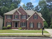 Charming two-story brick home with well-manicured lawn and mature trees provides great curb appeal at 1988 Greensferry Gln, Lawrenceville, GA 30043