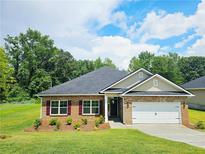 Charming brick home with a well-manicured lawn, attached garage, and beautiful landscaping at 112 Scarlett Place Dr, Bowdon, GA 30108