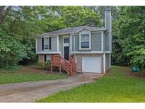 Charming split-level home with gray siding, brick accents, and a one-car garage nestled in lush greenery at 3498 Newberry Trl, Decatur, GA 30034