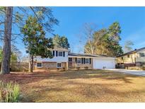 Charming home with brick and siding, set on a well-maintained lawn with mature trees under a beautiful blue sky at 6071 Cristie Dr, Ellenwood, GA 30294