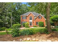Charming two-story brick home with a well-manicured lawn and mature trees at 6435 Ivey Creek Cir, Cumming, GA 30040