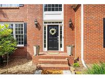 Charming brick home entrance with black door, decorative wreath, and potted plants at 6435 Ivey Creek Cir, Cumming, GA 30040
