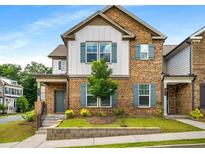 Charming brick townhome with blue shutters, a cozy front porch, and a well-manicured lawn at 947 Edwin Ln, Sugar Hill, GA 30518
