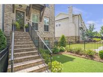 Inviting brick townhouse with landscaped front yard and stairway leading to the main entrance at 134 Everley Walk, Alpharetta, GA 30009