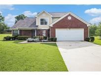 Charming two-story brick home with a well-manicured lawn and a two-car garage on a sunny day at 1698 Bennett Dr, Mcdonough, GA 30253