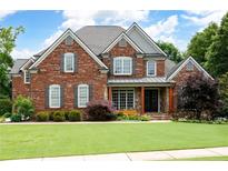 Charming red brick home with a well-manicured lawn, gray shutters, and a welcoming front porch at 2260 Falkirk Pointe Dr, Marietta, GA 30062