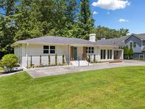 Charming brick home with lush lawn, new landscaping, covered carport and inviting updated entrance at 401 Cottonwood Dr, Woodstock, GA 30189