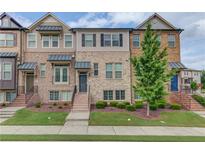 Beautiful townhome featuring a brick facade, manicured lawn, and inviting entrance at 4405 Donahue Ave, Sugar Hill, GA 30518