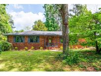 Charming brick home with well-maintained lawn, gray shutters and mature trees providing shade at 3219 W Manor Ln, Atlanta, GA 30311