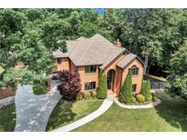 Stunning two-story brick home featuring a well-manicured lawn, mature trees, and a circular driveway at 5121 Hunters Hill Sw Cv, Lilburn, GA 30047