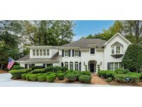 Beautiful two-story home with white painted brick, manicured landscaping and an American flag at 8480 Valemont Dr, Sandy Springs, GA 30350