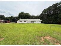 Inviting ranch-style home boasts a sprawling lawn, complemented by mature trees and a quaint, covered front porch at 95 Oak Grove Cir, Mcdonough, GA 30253