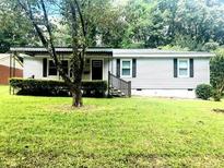 Charming single-story home with vinyl siding, mature trees, and a well-maintained front lawn at 6471 Ansley Blvd, Lithia Springs, GA 30122