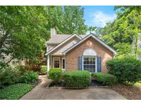 Charming single-story brick home with mature landscaping, blue shutters, and a cozy front porch at 1901 Brittania Cir, Woodstock, GA 30188