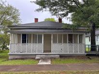 Charming home featuring a quaint front porch with white lattice railing and mature trees at 29 Ivy St, Porterdale, GA 30014