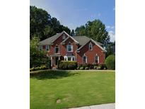 Charming two-story red brick home with a well-manicured lawn and mature landscaping, showcasing classic suburban appeal at 4265 Lansmoore Xing, Suwanee, GA 30024
