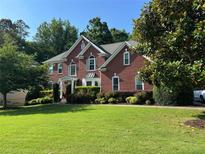 Charming brick home with a manicured lawn and mature trees showcasing classic architectural details at 4265 Lansmoore Xing, Suwanee, GA 30024