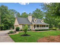 Charming home featuring a welcoming front porch, lush landscaping, and attached garage at 1420 Pilgrim Rd, Cumming, GA 30040