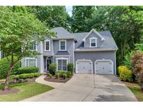 Charming gray two-story home with a well-manicured lawn, lush landscaping, and a two-car garage at 115 Township Ct, Woodstock, GA 30189