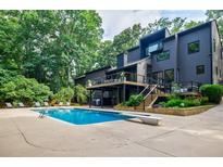 Stunning backyard featuring a large inground pool, diving board, sun loungers, and multilevel deck overlooking lush greenery at 1510 Chevron Dr, Sandy Springs, GA 30350