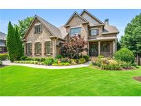 Beautiful brick home featuring manicured landscaping, lush green lawn and charming covered front porch at 2953 Kings Walk Ave, Marietta, GA 30062