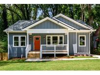 Charming blue home with a welcoming front porch and an orange front door nestled among lush trees at 387 Hillside Sw Dr, Atlanta, GA 30310