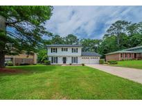 Charming two-story home featuring classic black shutters, lush green lawn and an attached two car garage at 4732 Manly Ct, Stone Mountain, GA 30088