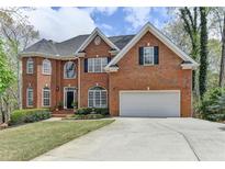 Charming two-story red brick home with a well-manicured lawn and attached two car garage at 525 Water Shadow Ln, Alpharetta, GA 30022